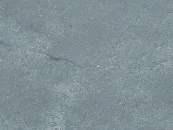 Asphalt texture, blue-grey in color, with blotchy light areas and small amounts of irregular cracking.